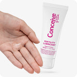 For Conceive Plus Max Combo - Fertility Lubricant Bundle (PT), image of 75ml fertility lubricant tube held next to an open palm with a visible amount of clear lubricant gel, demonstrating product texture and ease of application, styled on a clean white background.